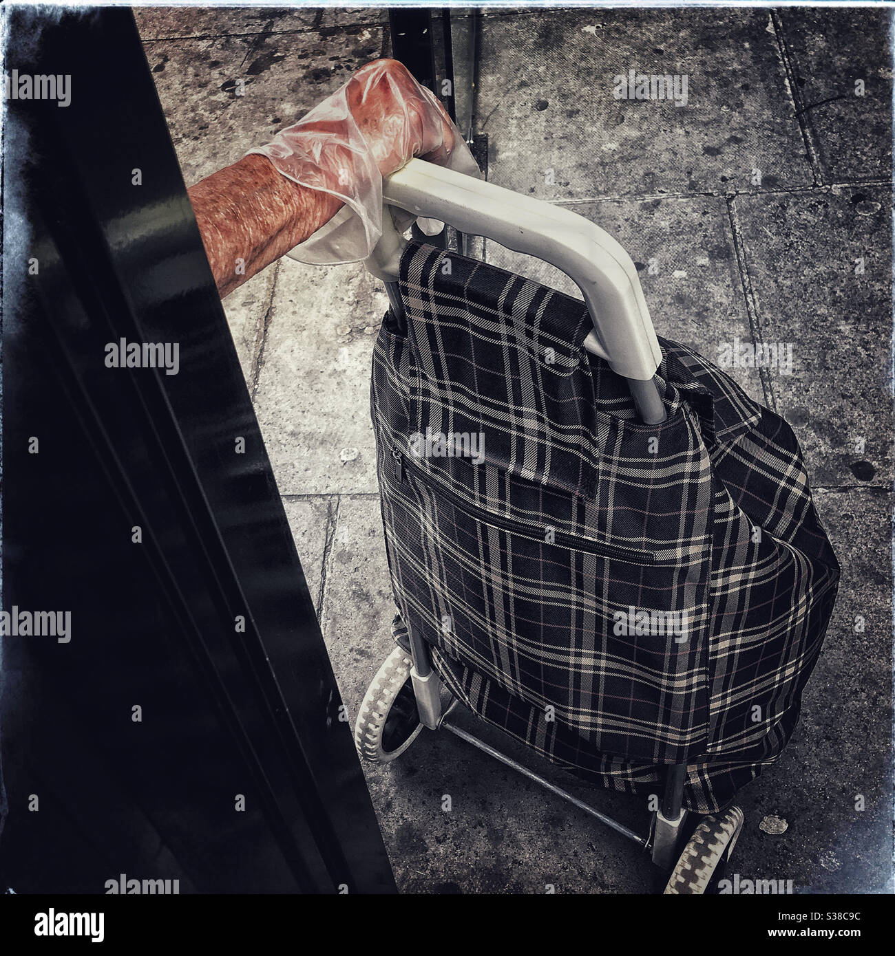 La main dans un gant en plastique saisit la poignée d'un chariot à provisions - Image de stock capturée avec un smartphone