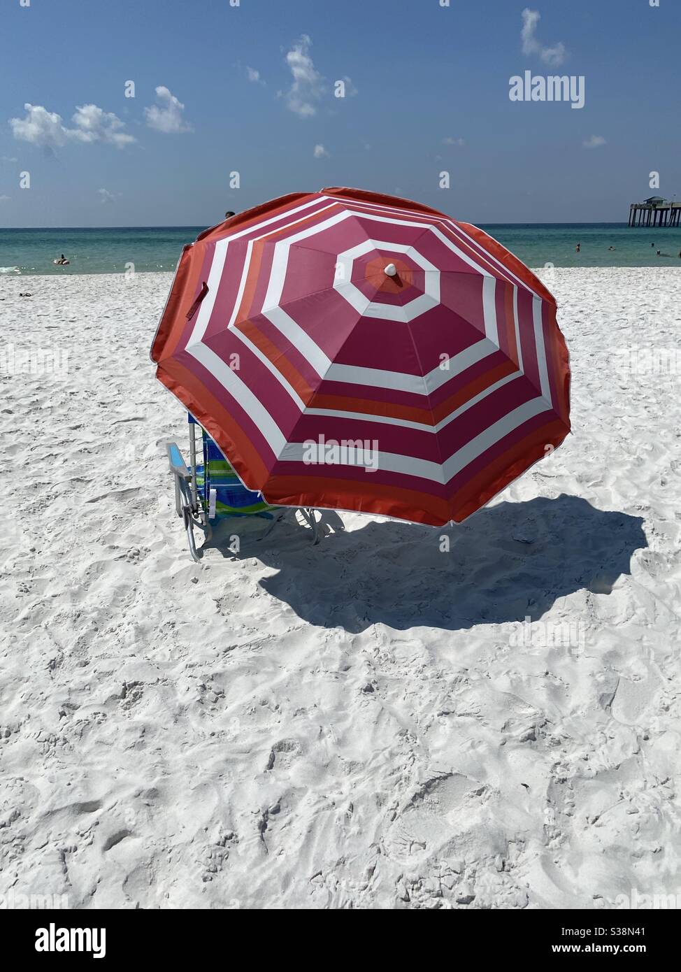 Parasol coloré et chaise sur plage de sable blanc avec vue sur l'eau Banque D'Images