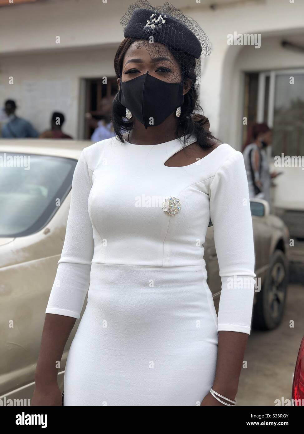 Jeune femme noire sur robe blanche et masque noir Banque D'Images