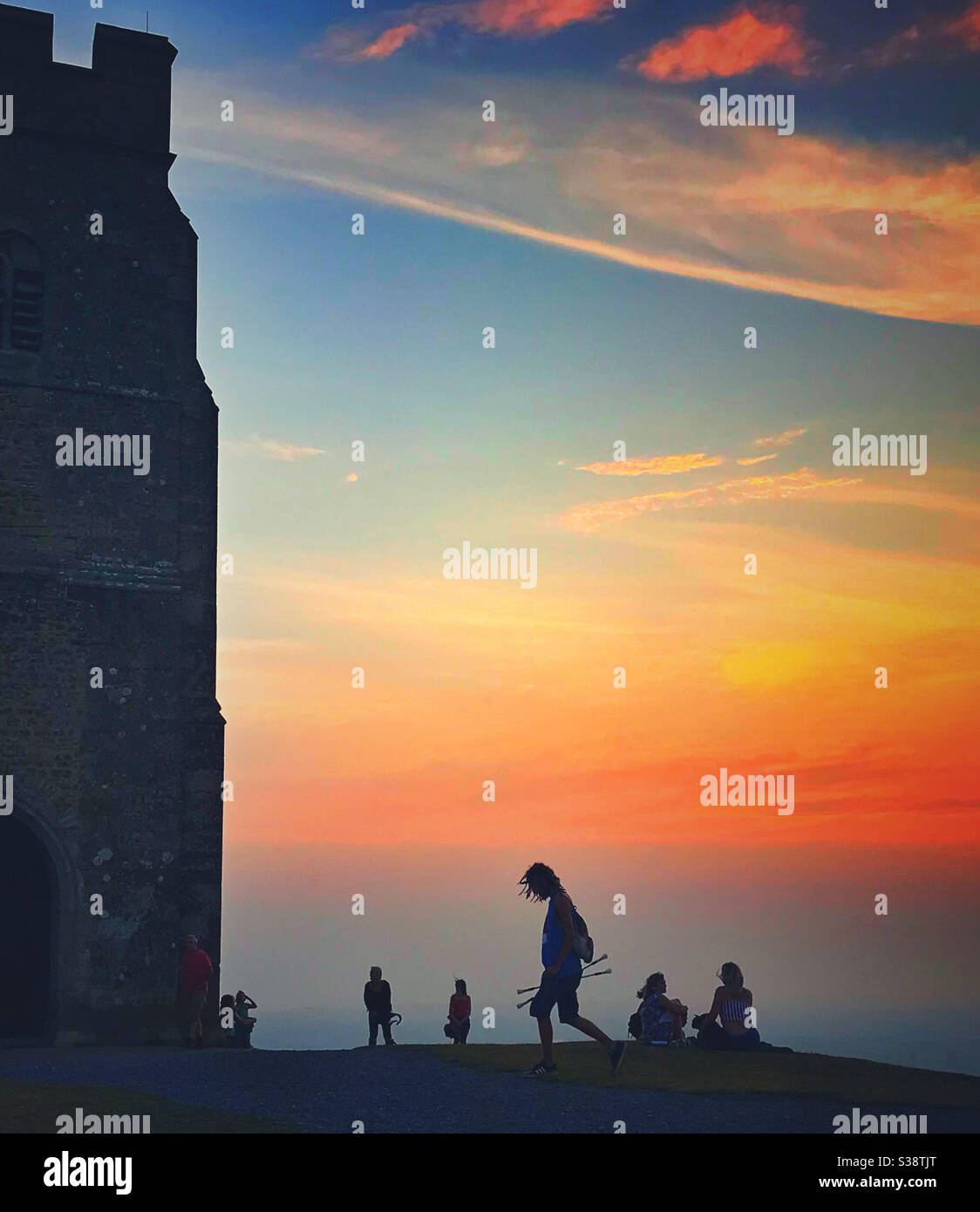 Silhouettes au sommet de Glastonbury Tor contre un coucher de soleil lumineux Banque D'Images