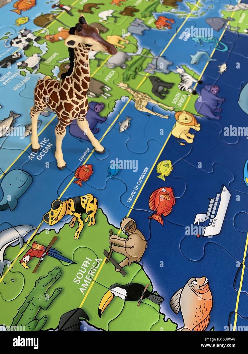 Girafe jouet sur la carte du puzzle du monde Banque D'Images