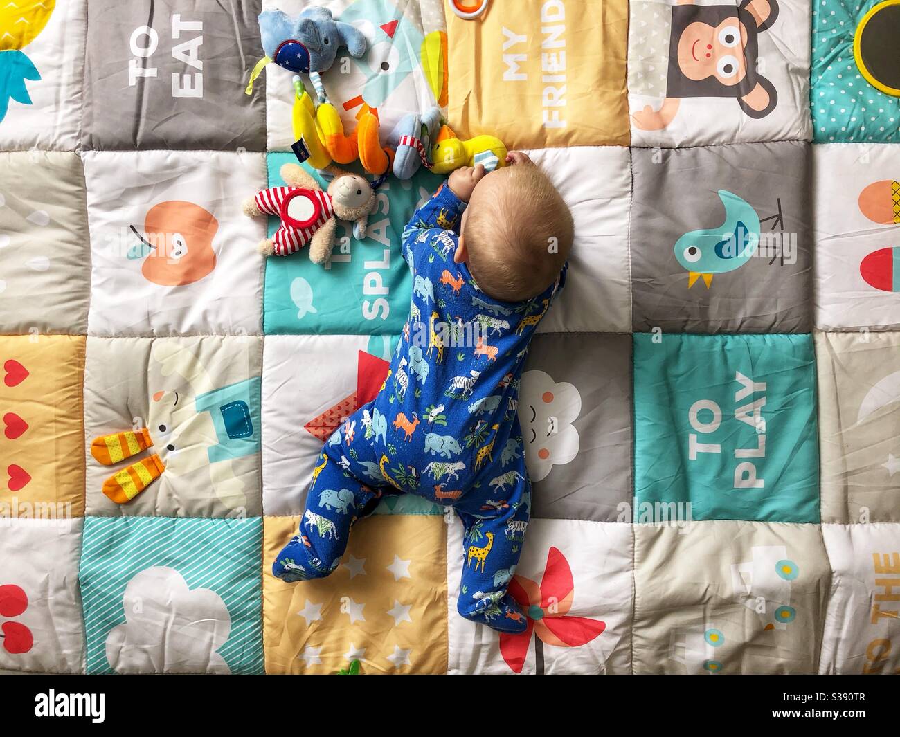 bébé de 5 mois jouant sur un tapis de jeu coloré Banque D'Images