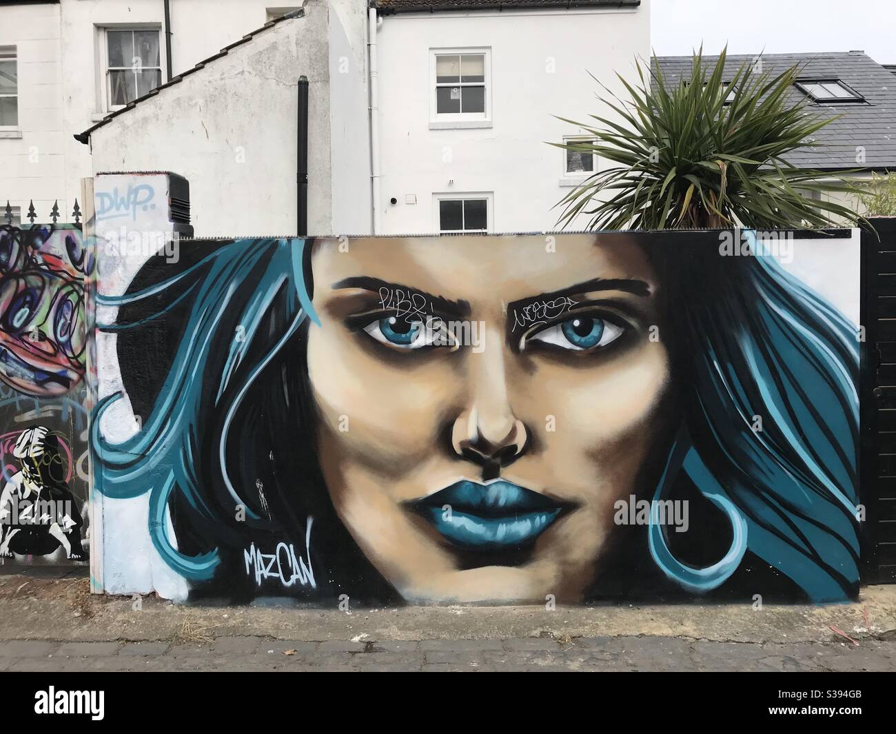 Dame aux cheveux bleus et aux lèvres peint graffiti sur la brique Mur à Brighton, Royaume-Uni Banque D'Images