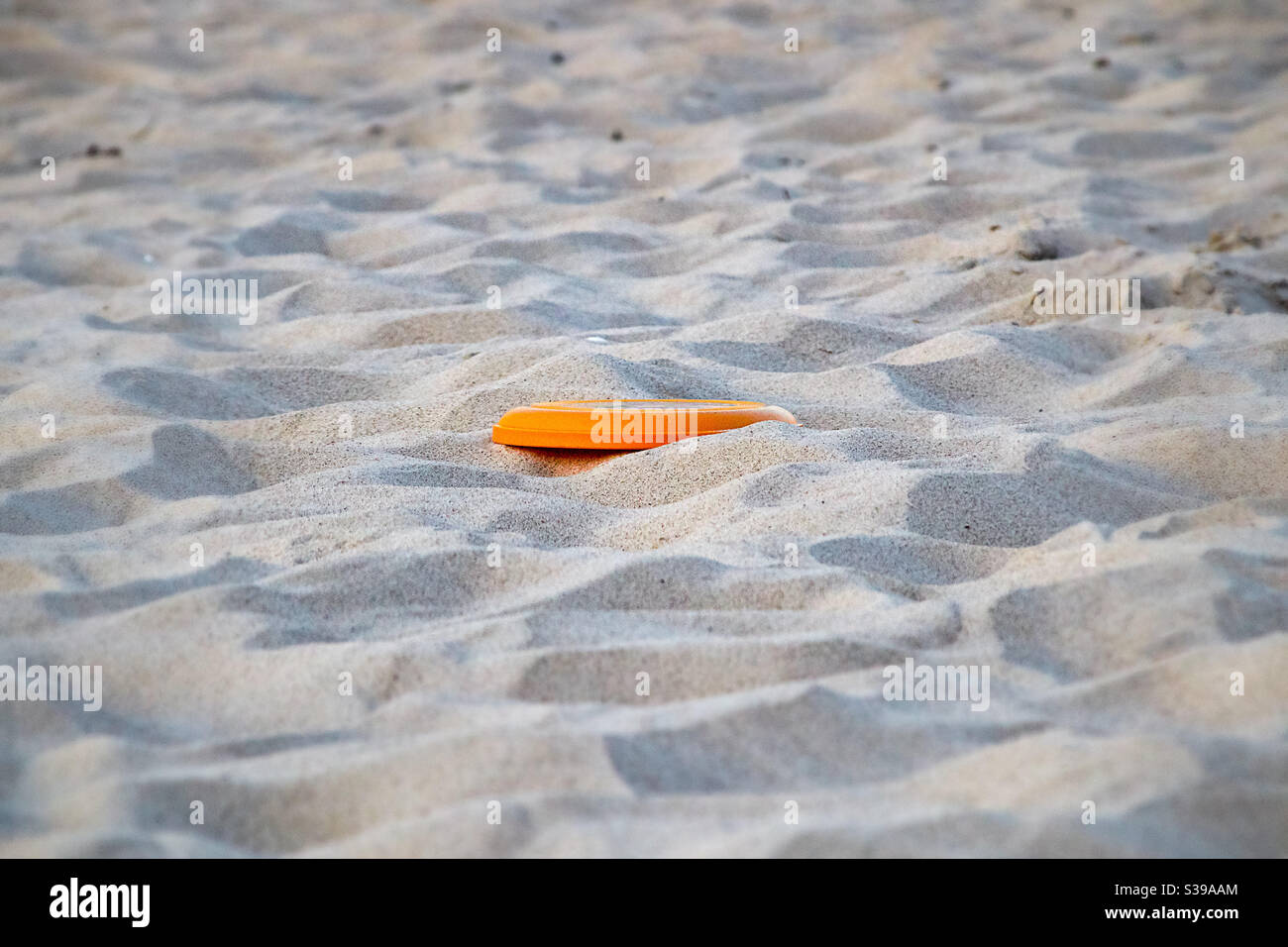 Orange jaune Frisbee se trouve dans la pause de jeu de temps libre dans le sable fin de la plage Banque D'Images