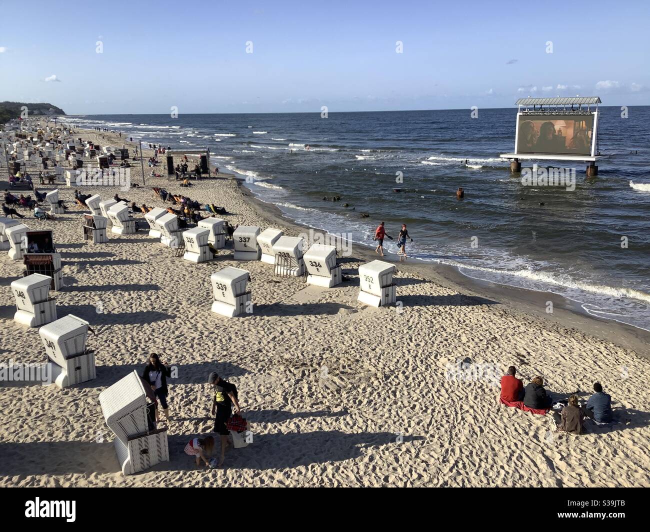 Les gens sur la plage regardant un film sur un énorme moniteur LED de visionneuse (Kino am Meer) debout dans les eaux peu profondes de l'océan, Pier de Heringsdorf, Mer Baltique, Usedom, Mecklembourg Vorpommern, Allemagne, Europe Banque D'Images