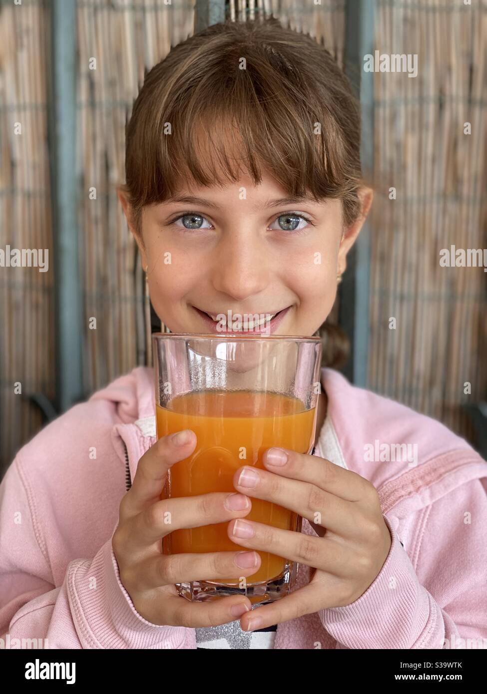 Bonne fille garde un verre de jus d'orange frais Banque D'Images