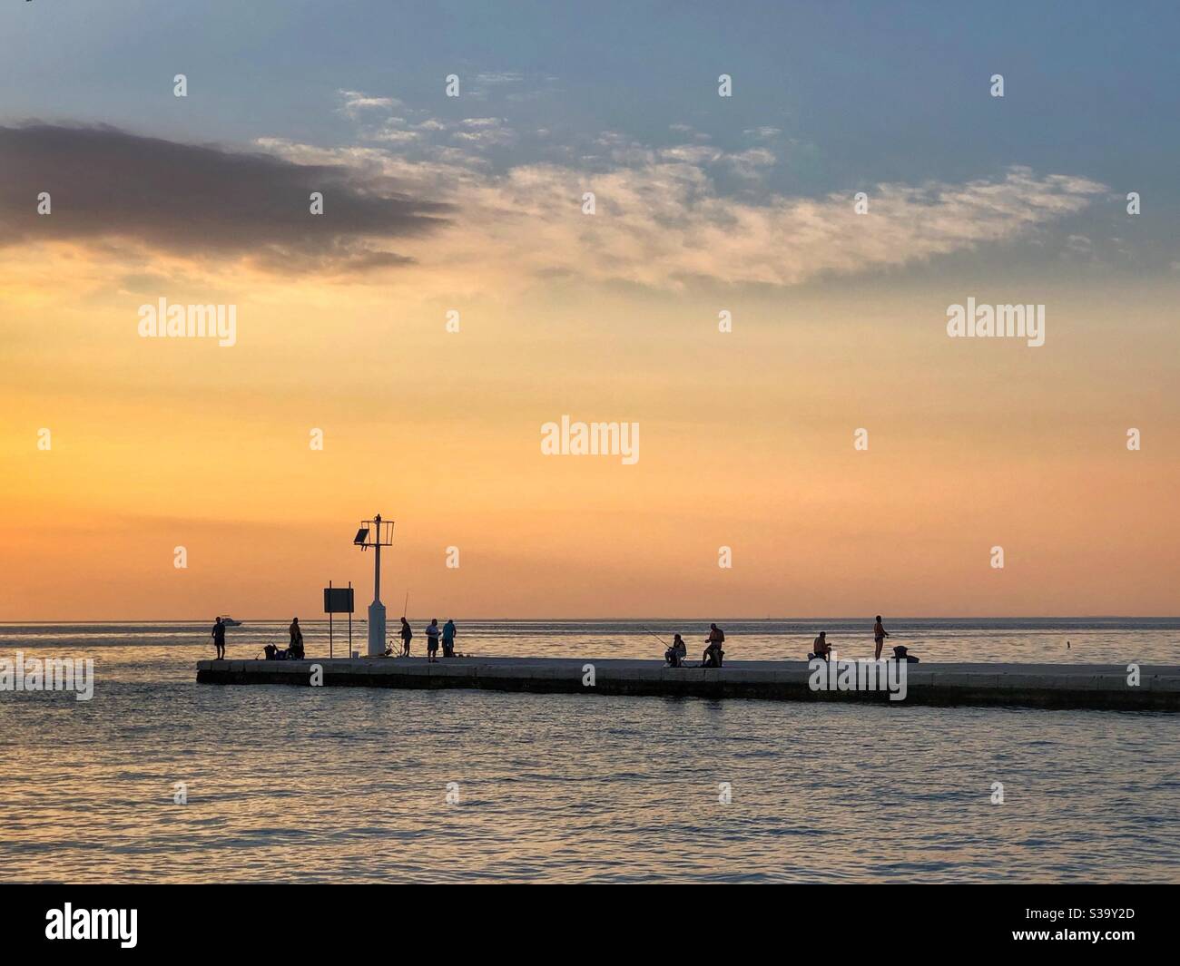 Pêcheurs qui pêchent avec des cannes à pêche au coucher du soleil - Strunjan, Slovénie - Image de stock capturée avec un smartphone