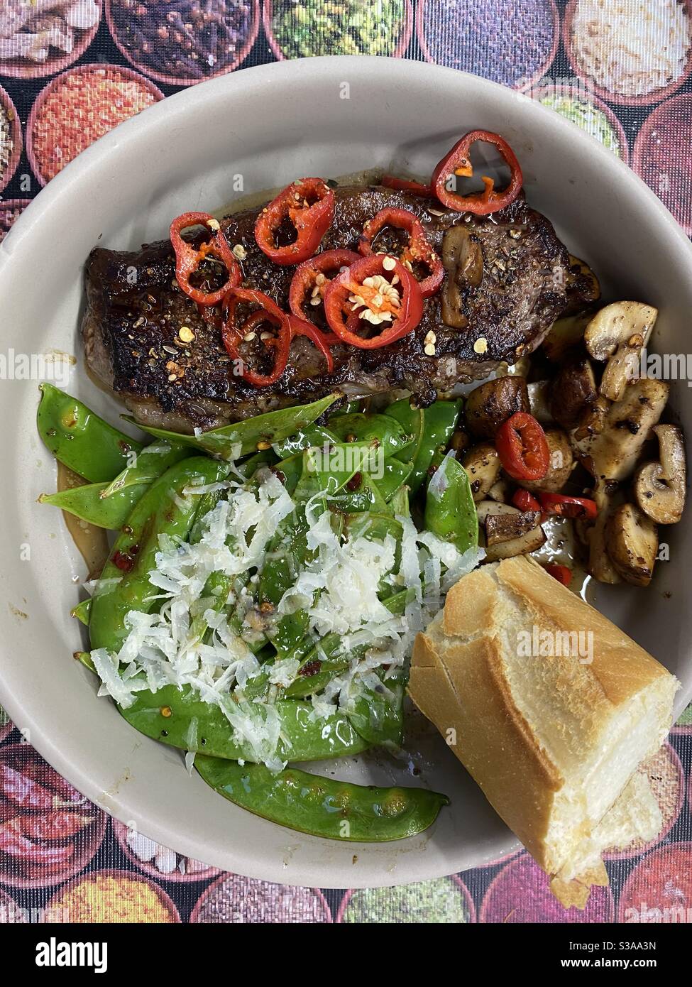 Steak de bœuf, piment rouge, rôle croustillant frais, beurre de citron vert, pois mange-tout et parmesan Banque D'Images
