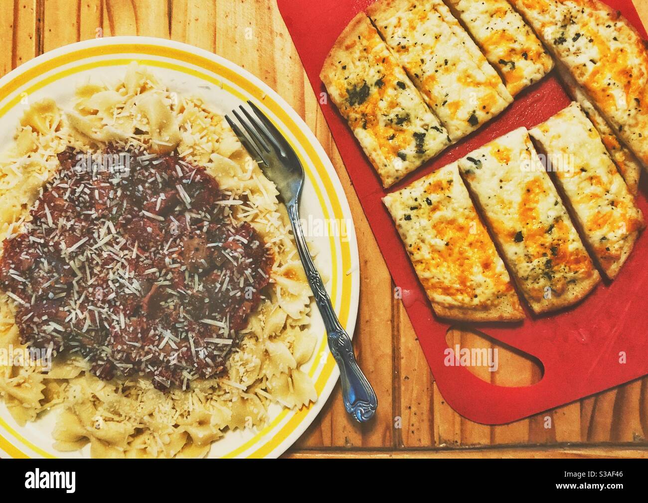 Pâtes farfalle à nouer avec sauce tomate maison, parmesan et pain naan au fromage à l'ail sur une table en bois Banque D'Images