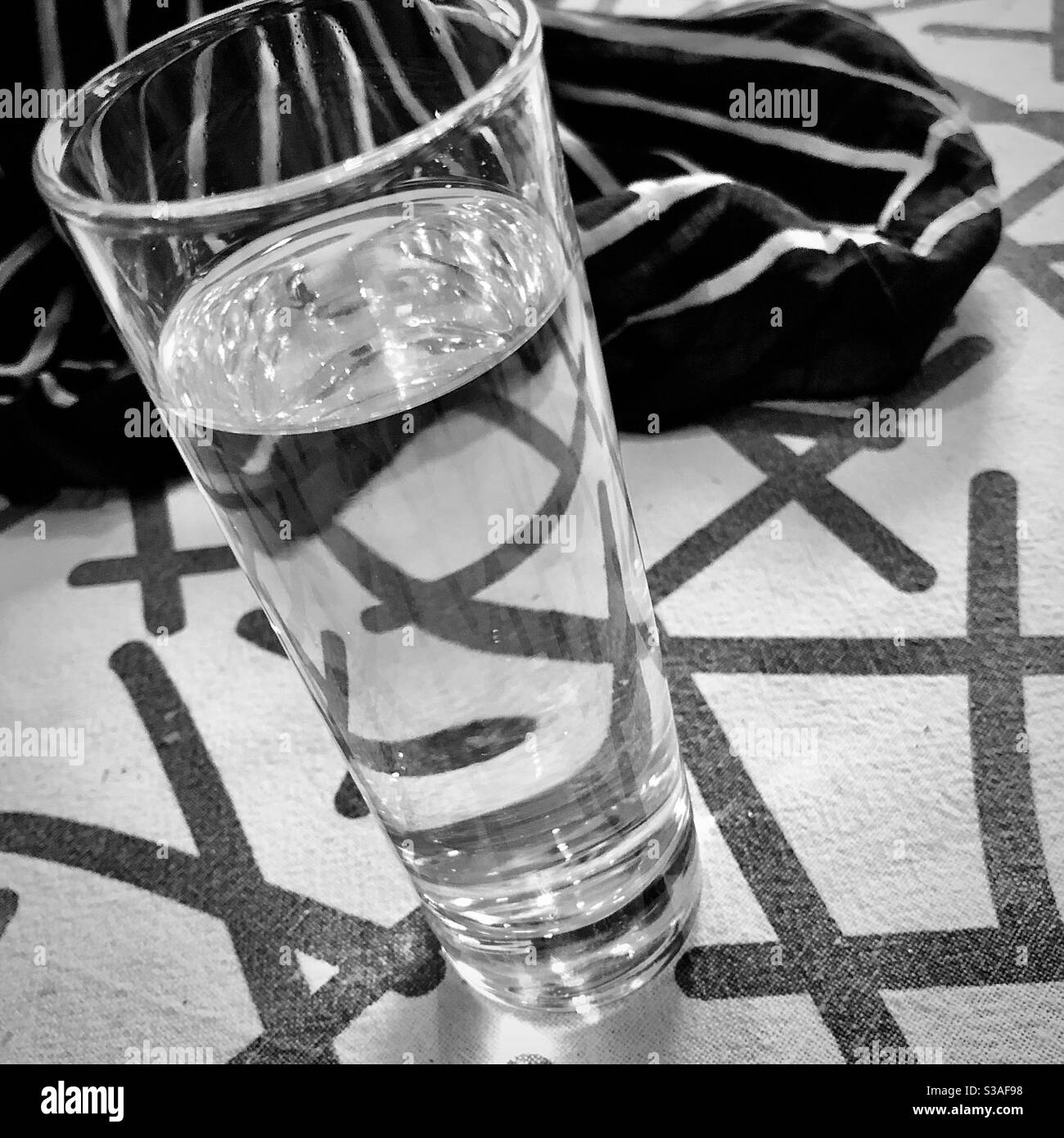 Verre d'eau noir et blanc sur nappe à motifs. Banque D'Images