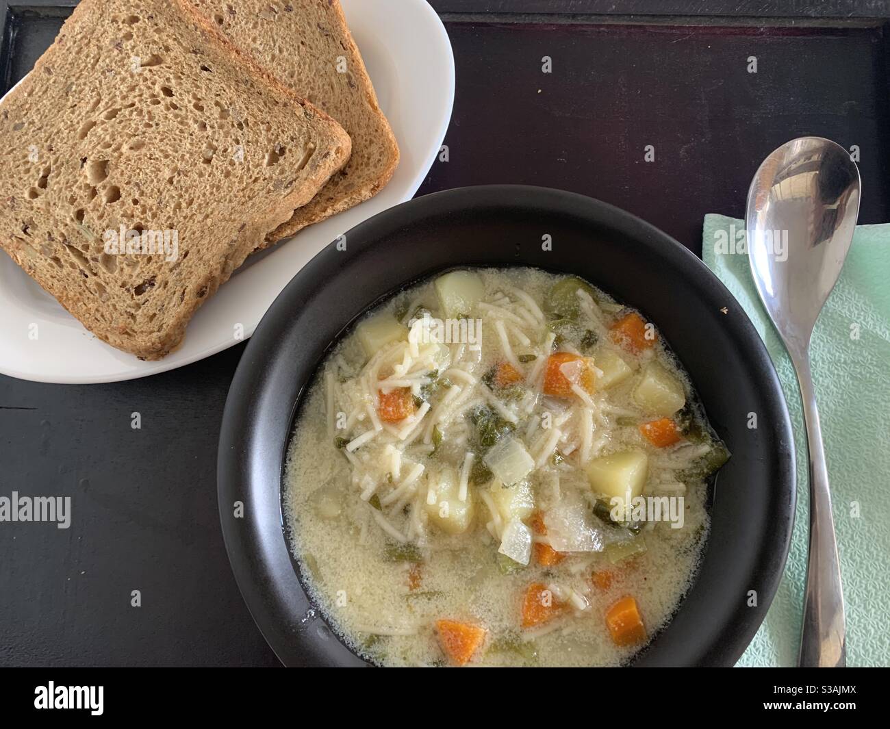 Nourriture, soupe, légumes, pommes de terre, carottes, nouilles, oignon, persil, pain, assiette, cuillère, serviettes Banque D'Images