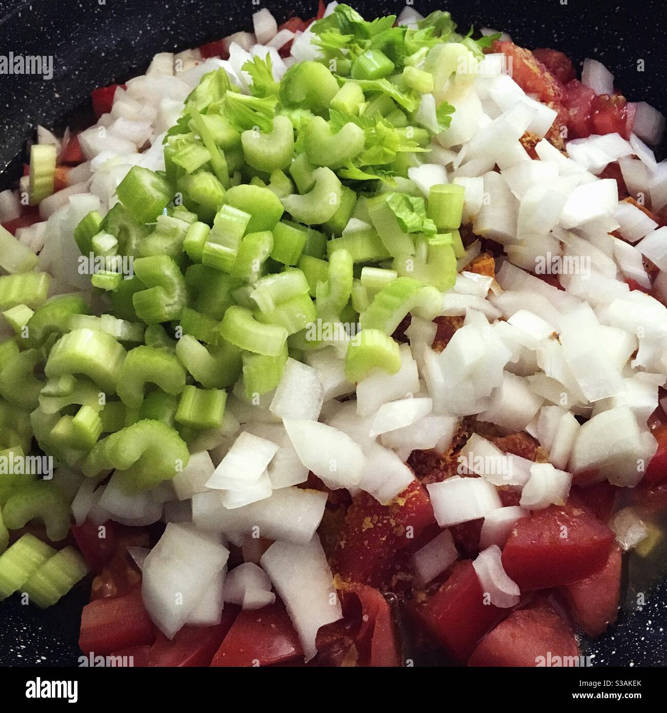 Tomates, oignons et céleri hachés dans une poêle prête à frire. Banque D'Images