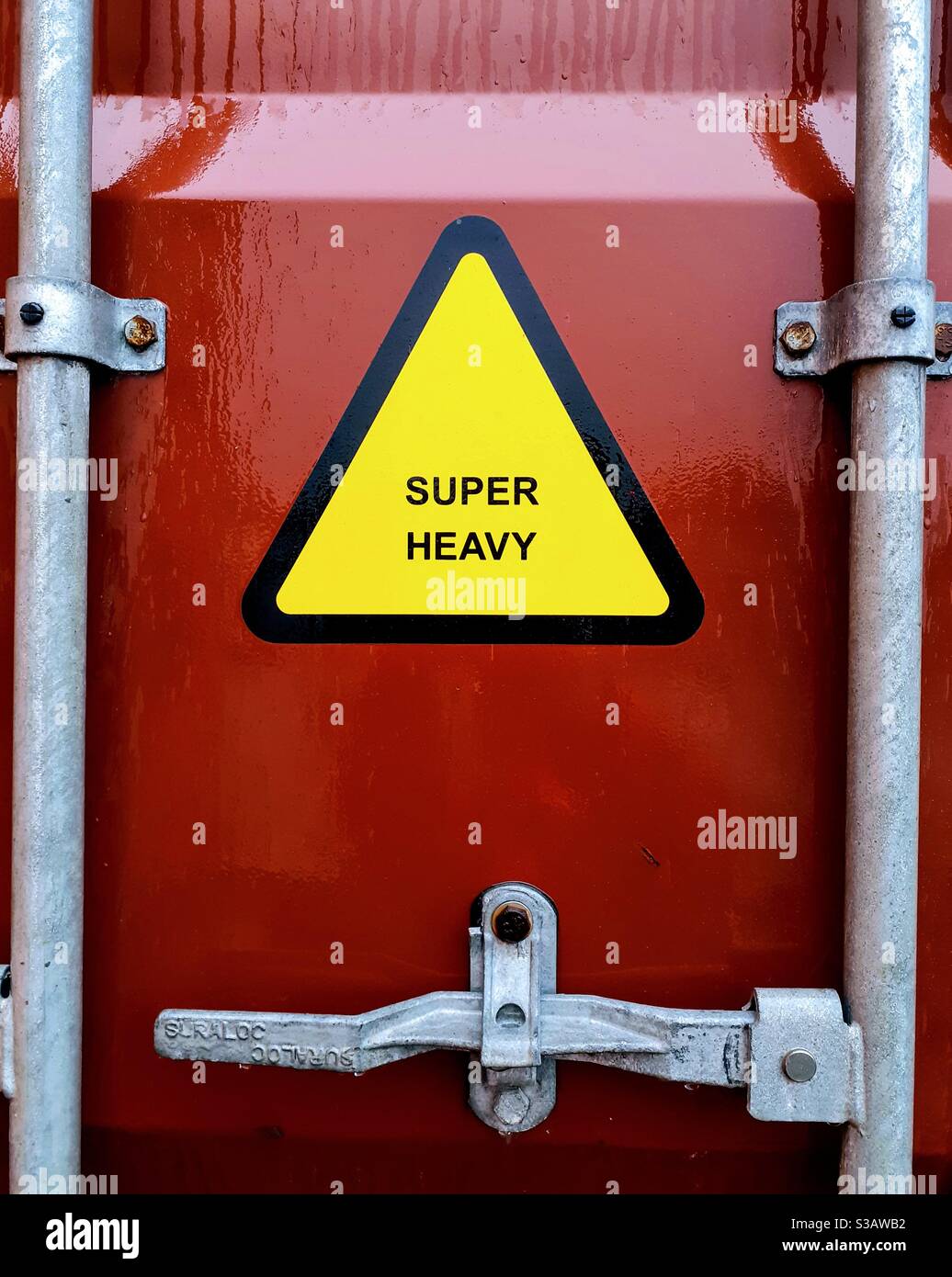 Un panneau d'avertissement triangulaire jaune sur le côté d'un conteneur d'expédition ou caisse de chargement avertissement d'un très lourd poids à l'intérieur - Image de stock capturée avec un smartphone