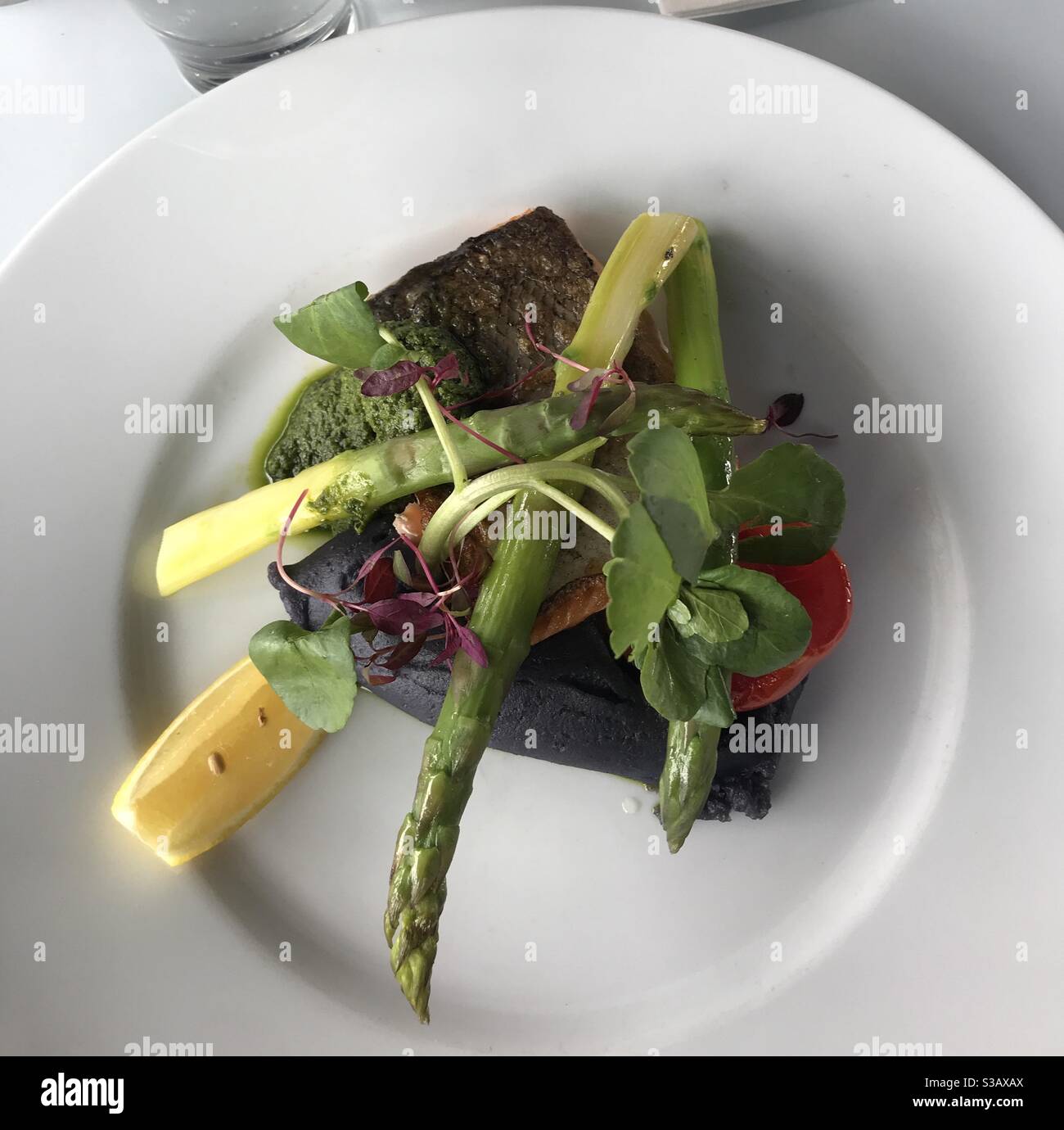 Saumon rôti, purée d'huile d'olive de pomme de terre Violetta, tomate lentement cuite avec asperges grillées au romarin, salsa verde - Image de stock capturée avec un smartphone