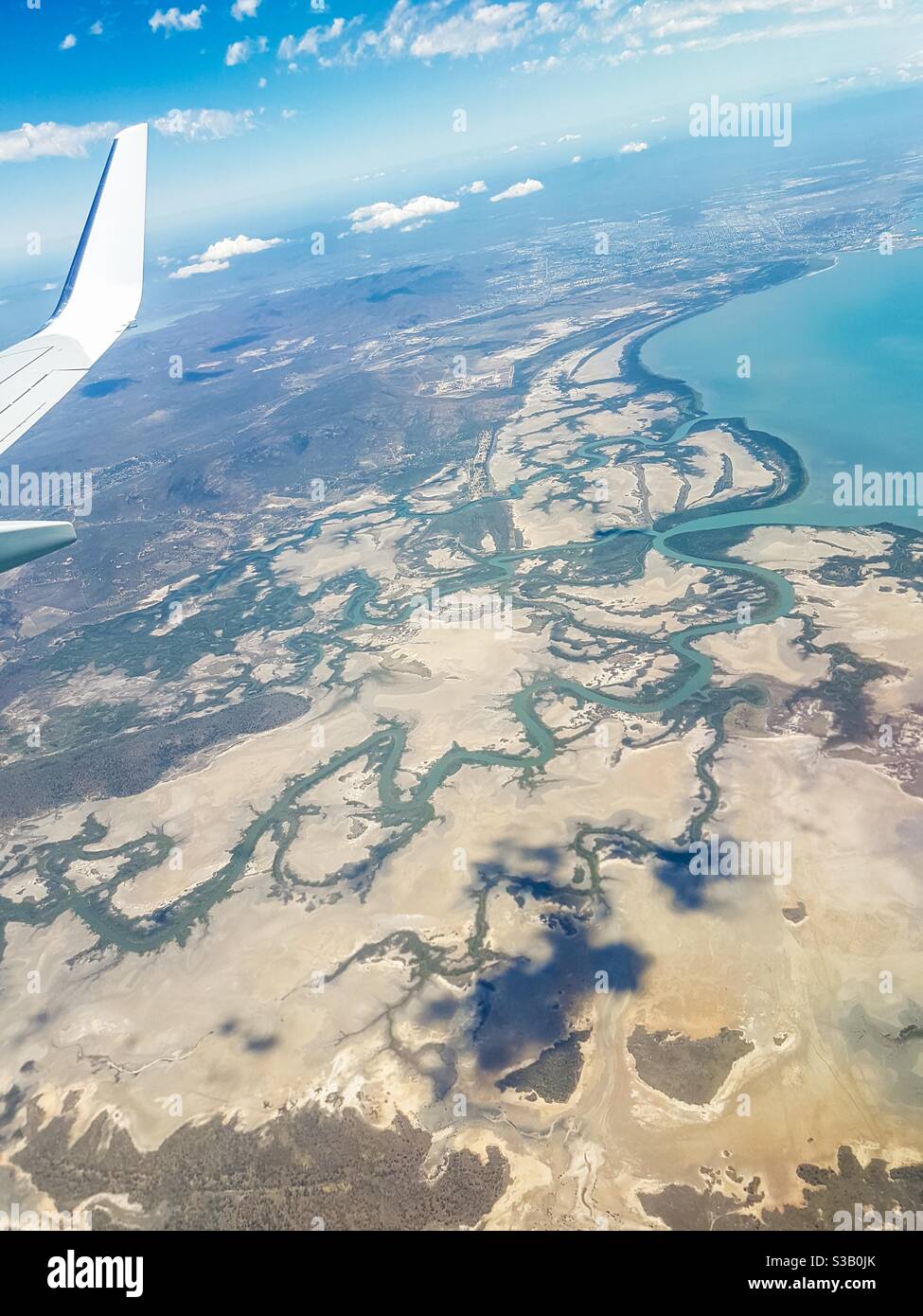 Image aérienne de la fenêtre d'avion des rivières et affluents menant à la mer juste au sud de Townsville, dans le nord du Queensland, en Australie - Image de stock capturée avec un smartphone