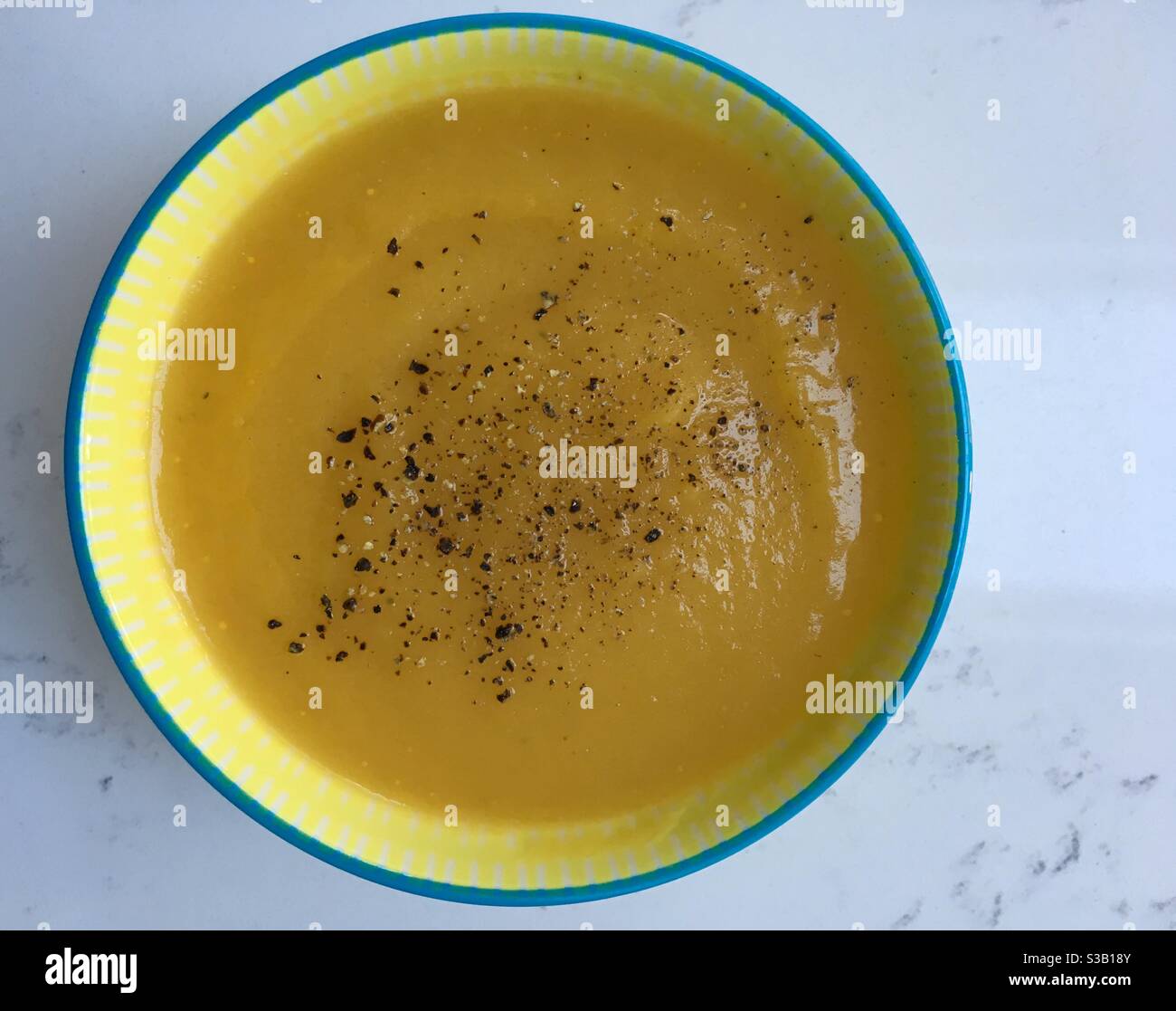 Bol jaune de soupe de potiron maison au poivre fraîchement concassé sur le dessus - Image de stock capturée avec un smartphone