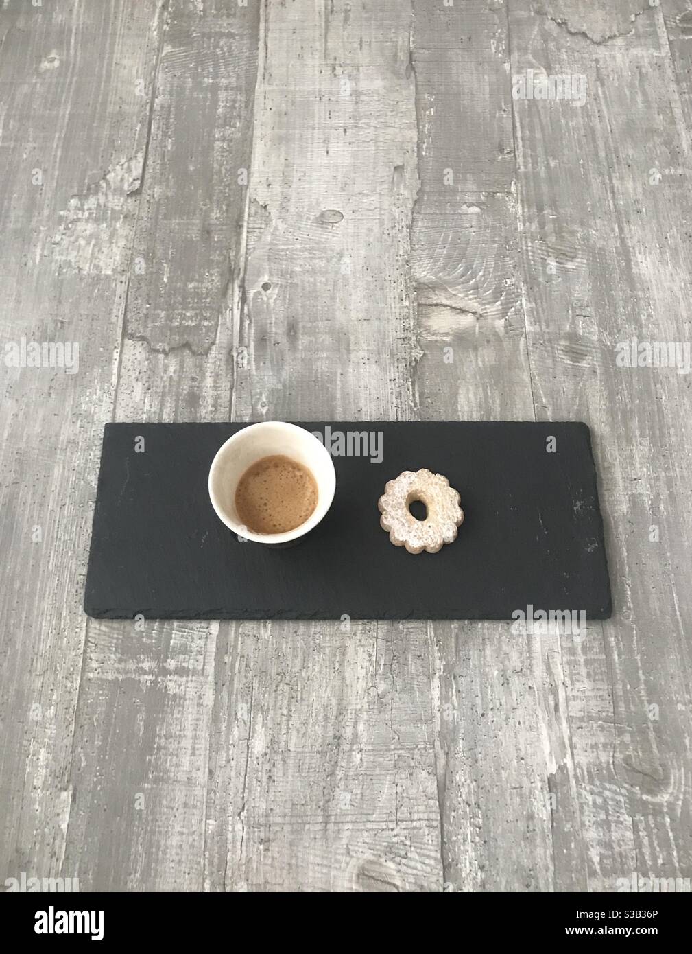 Un café expresso et un biscuit servis sur une ardoise noire sur fond en bois - Image de stock capturée avec un smartphone