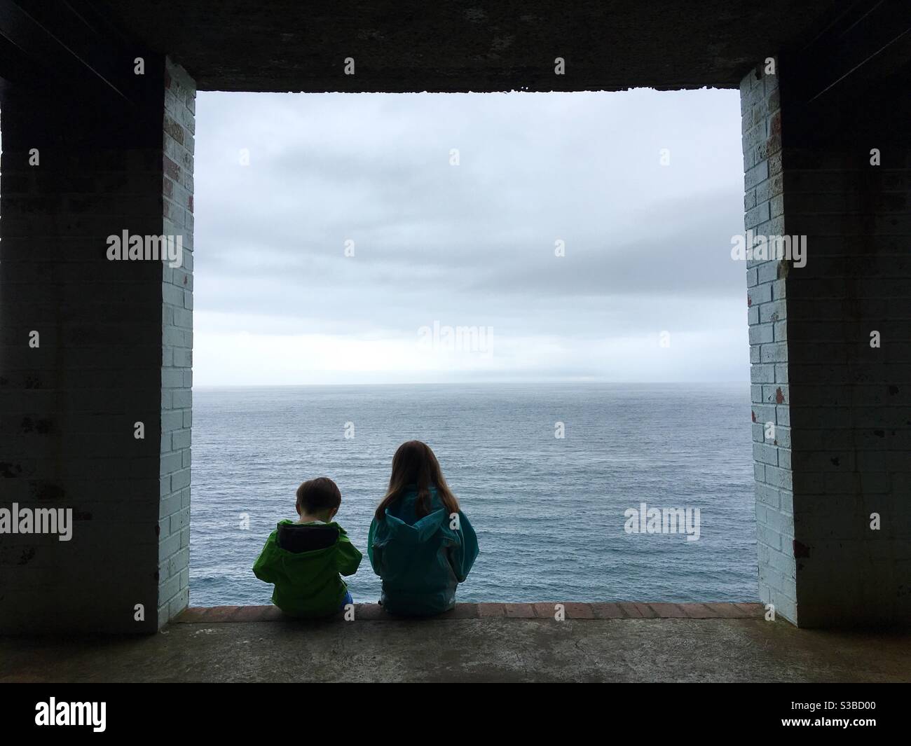 Deux enfants s'assoyant en regardant la vue sur la mer - Image de stock capturée avec un smartphone