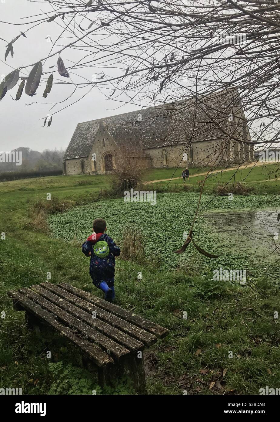 Enfant en train de courir avec la tithe Barn en arrière-plan Banque D'Images