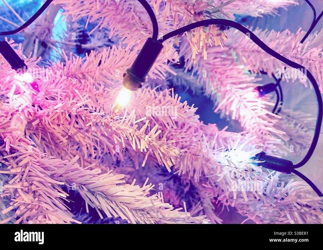 Une photo en gros plan de lumières de fées roses sur un arbre de Noël blanc. Décoration de fête. - Image de stock capturée avec un smartphone