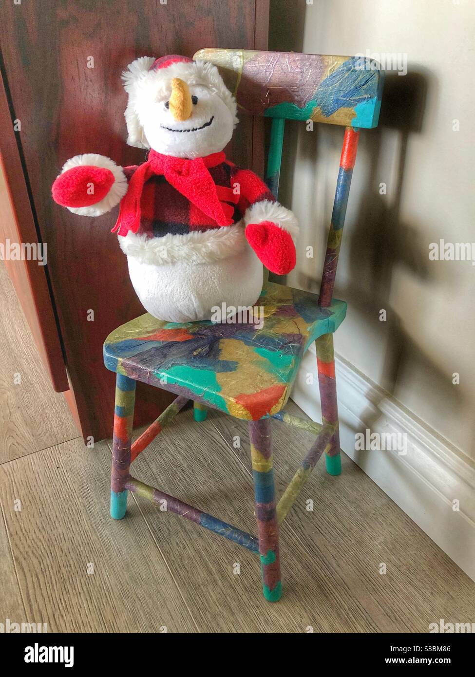 Givré le bonhomme de neige debout sur une chaise dans un coin confortable. Banque D'Images