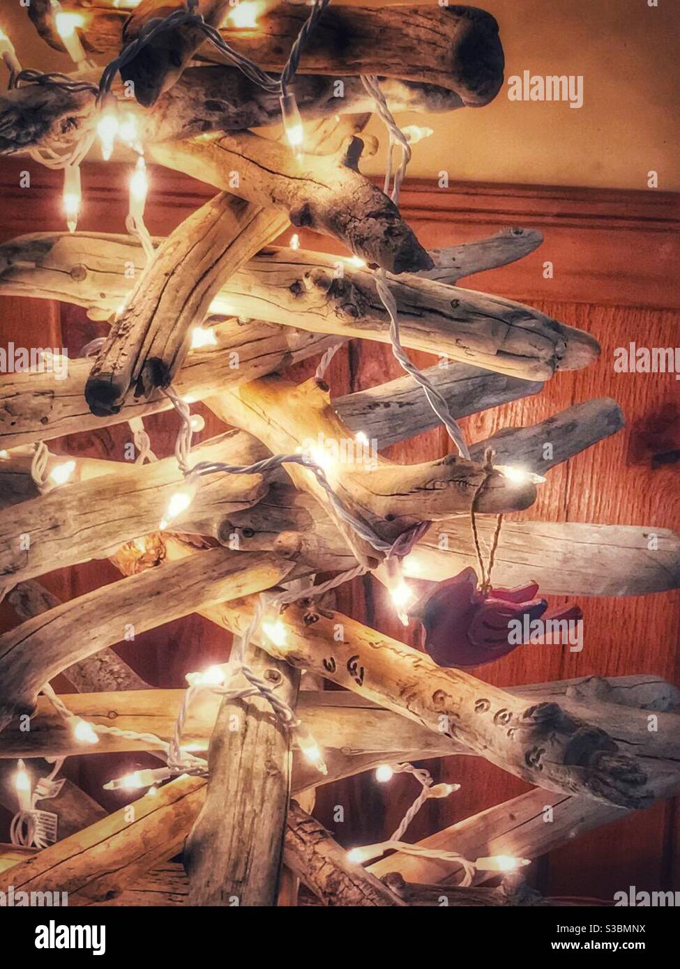 Vue rapprochée de l'arbre de Noël en bois flotté décoré de lumières blanches et un ornement cardinal en bois Banque D'Images