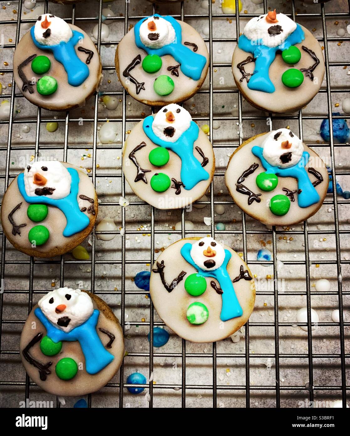 Des biscuits maison fantaisistes décorés comme des bonhommes de neige en fonte sèchent sur un support. Banque D'Images
