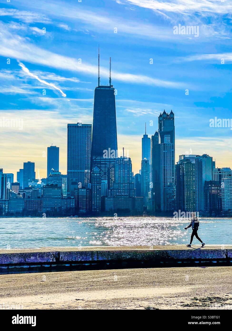 Homme marchant le long de la paroi de la mer à North Avenue Beach avec les gratte-ciel de Chicago en arrière-plan. Banque D'Images