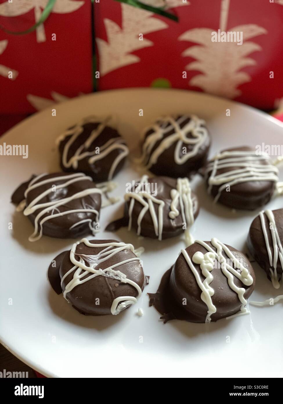 Biscuits enrobés de chocolat sur plaque blanche avec fond de Noël Banque D'Images