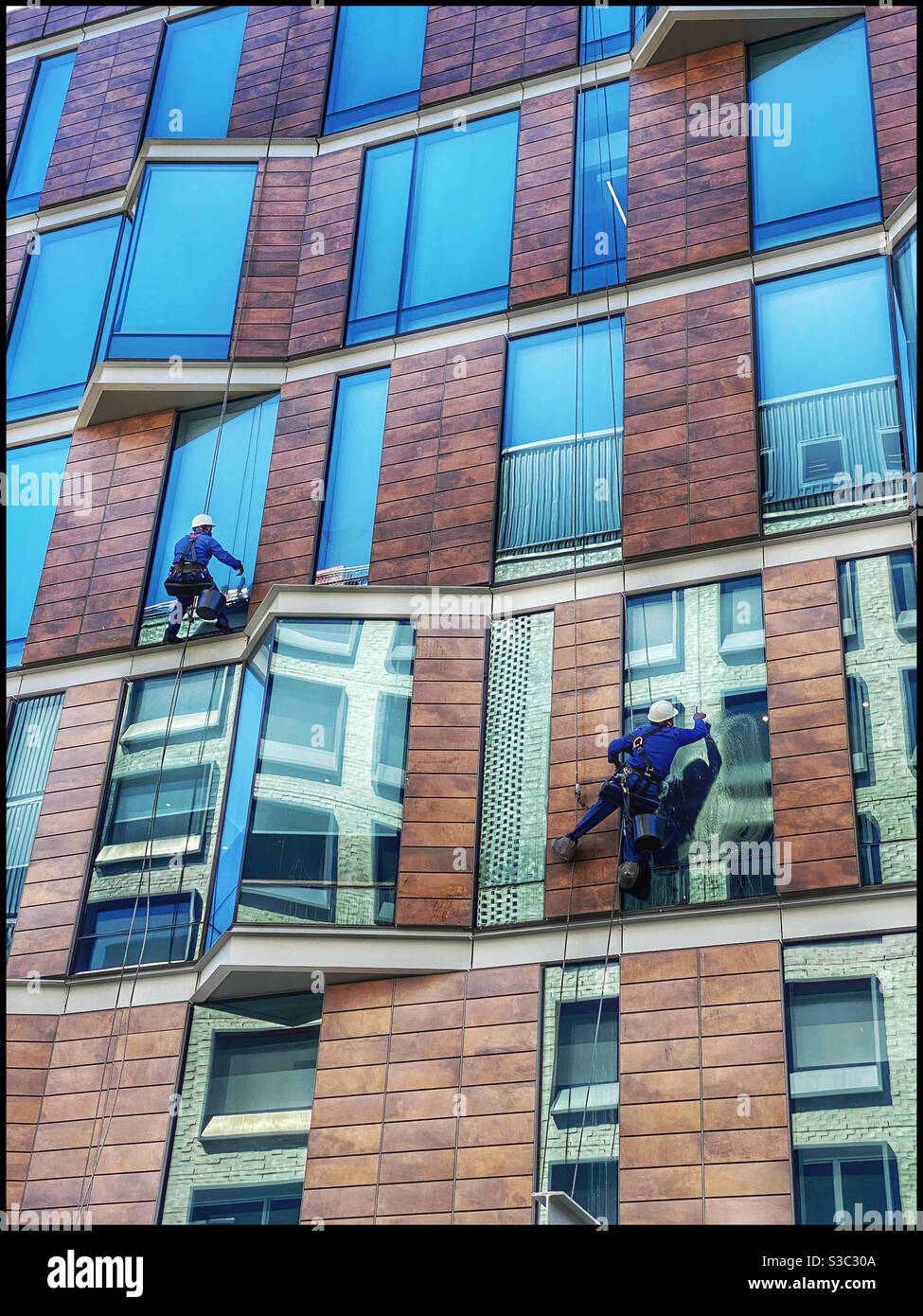Des nettoyeurs de fenêtres travaillent sur un bâtiment dans le quartier de Silo, au bord de l'eau de V&A, au Cap, en Afrique du Sud. Banque D'Images