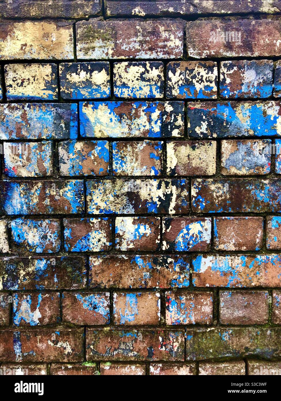 Vieux mur de briques avec couches de peinture écaillée et décolorée. Banque D'Images
