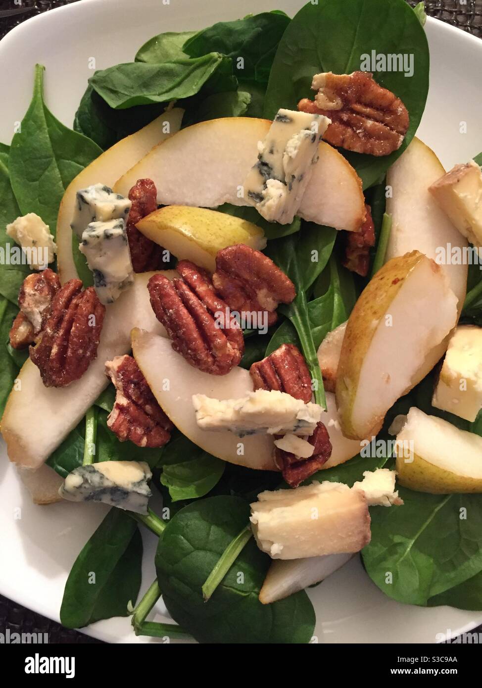 Assiette d'une salade gastronomique de pacanes confites, de poires fraîches et de fromage Stilton sur un lit d'épinards Banque D'Images