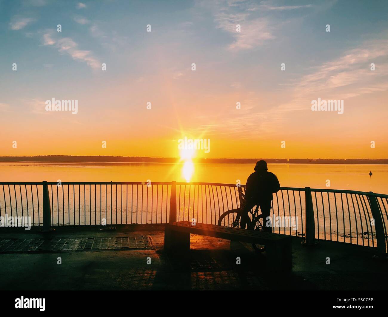 Un homme sur un vélo silhoueté regardant le coucher de soleil sur la rivière Mersey à Liverpool. Exercice quotidien du coronavirus - Image de stock capturée avec un smartphone