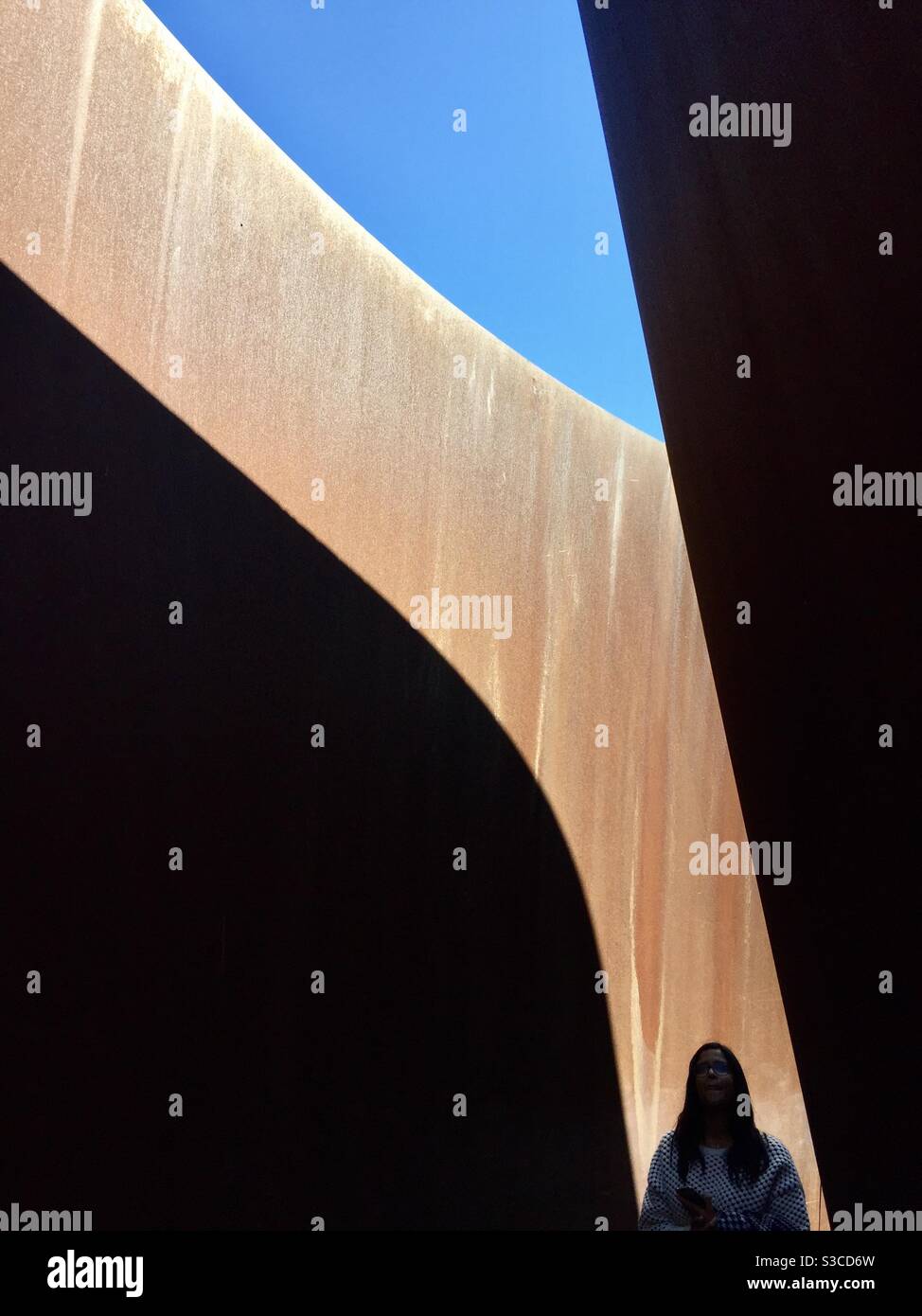 Une femme marche à travers une sculpture de Richard Serra intitulée « Sylvester, 2001 » au Glenstone Museum à Potomac, Maryland. - Image de stock capturée avec un smartphone