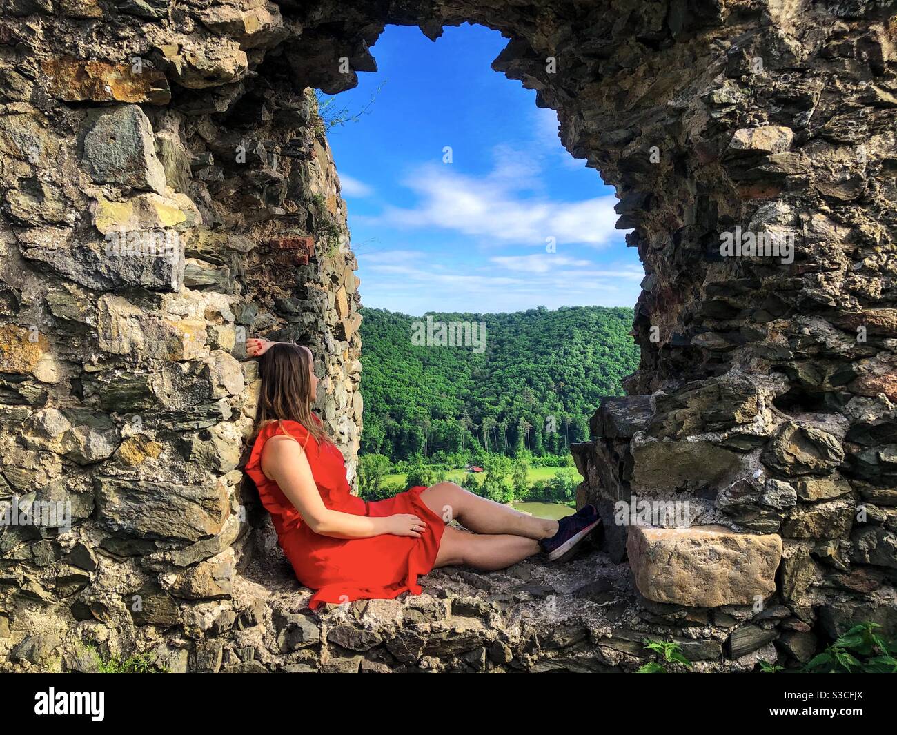 Femme en robe rouge reposant sur un vieux rebord de fenêtre en pierres - Image de stock capturée avec un smartphone