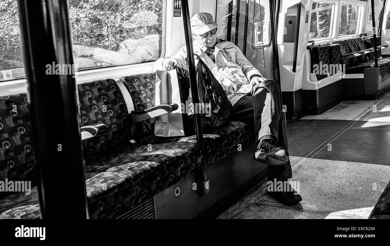 Vieil homme dormant dans le train Banque D'Images