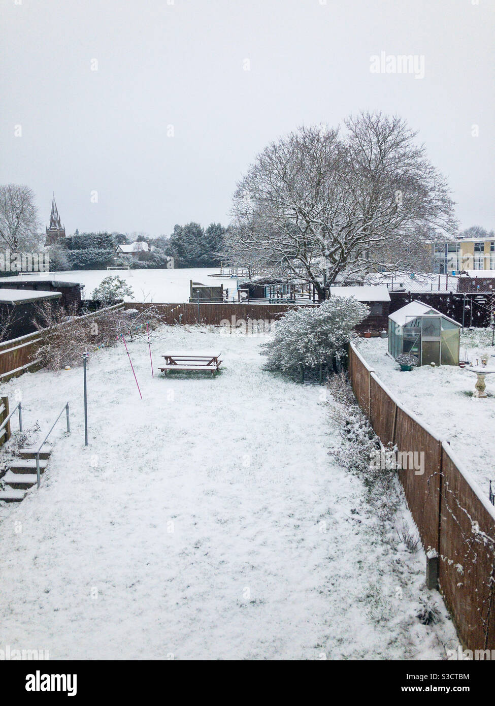 Un jardin et un champ au-delà couverts de neige. Banque D'Images