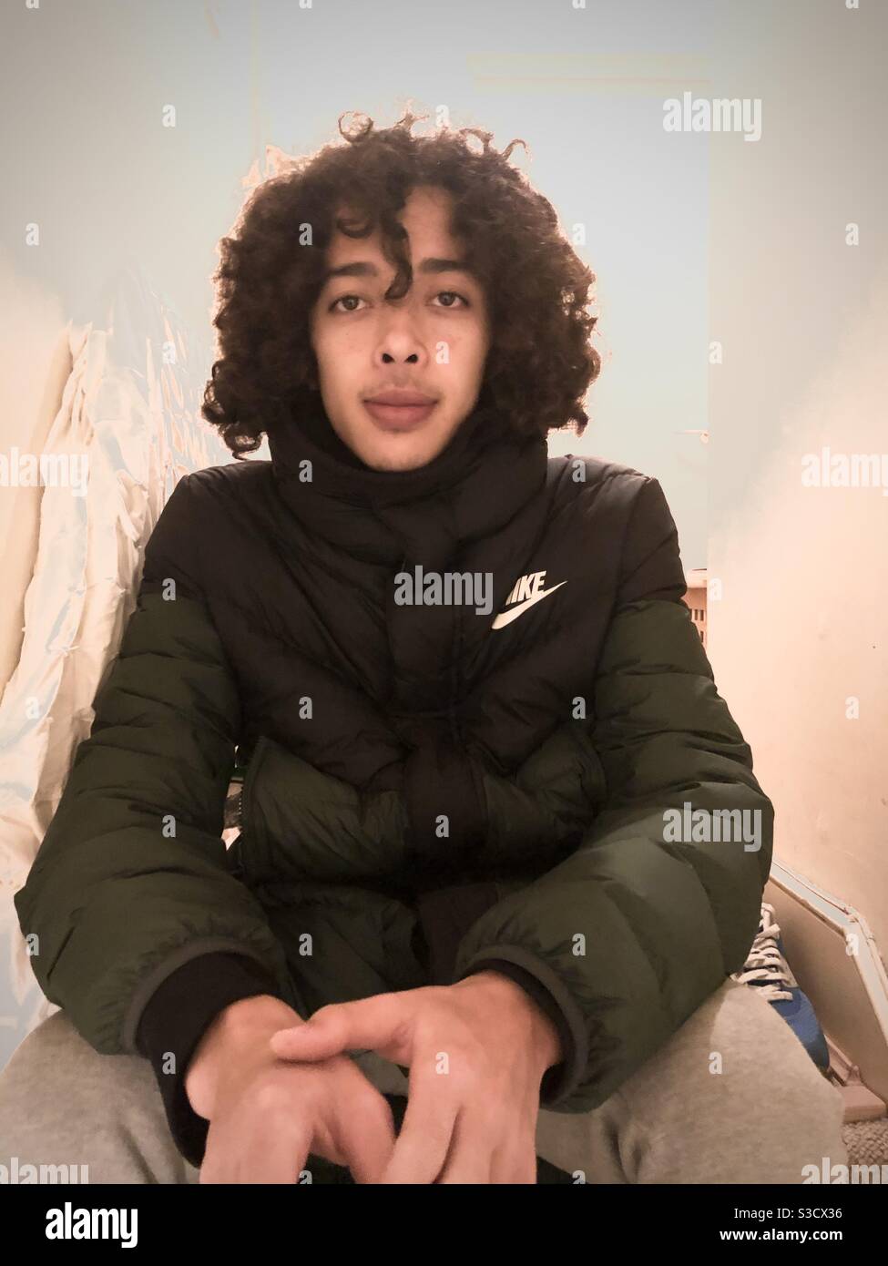 Jeune homme avec des cheveux bouclés surcultivés et bien attachés assis à la Haut des escaliers en janvier 2021 - Image de stock capturée avec un smartphone