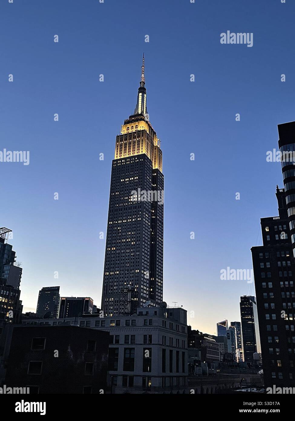 Le ciel bleu clair brille doucement sur les silhouettes de Midtown Manhattan, New York City, États-Unis, tandis que les lumières blanches brillantes du fier Empire State Building sont au centre de la scène. - Image de stock capturée avec un smartphone