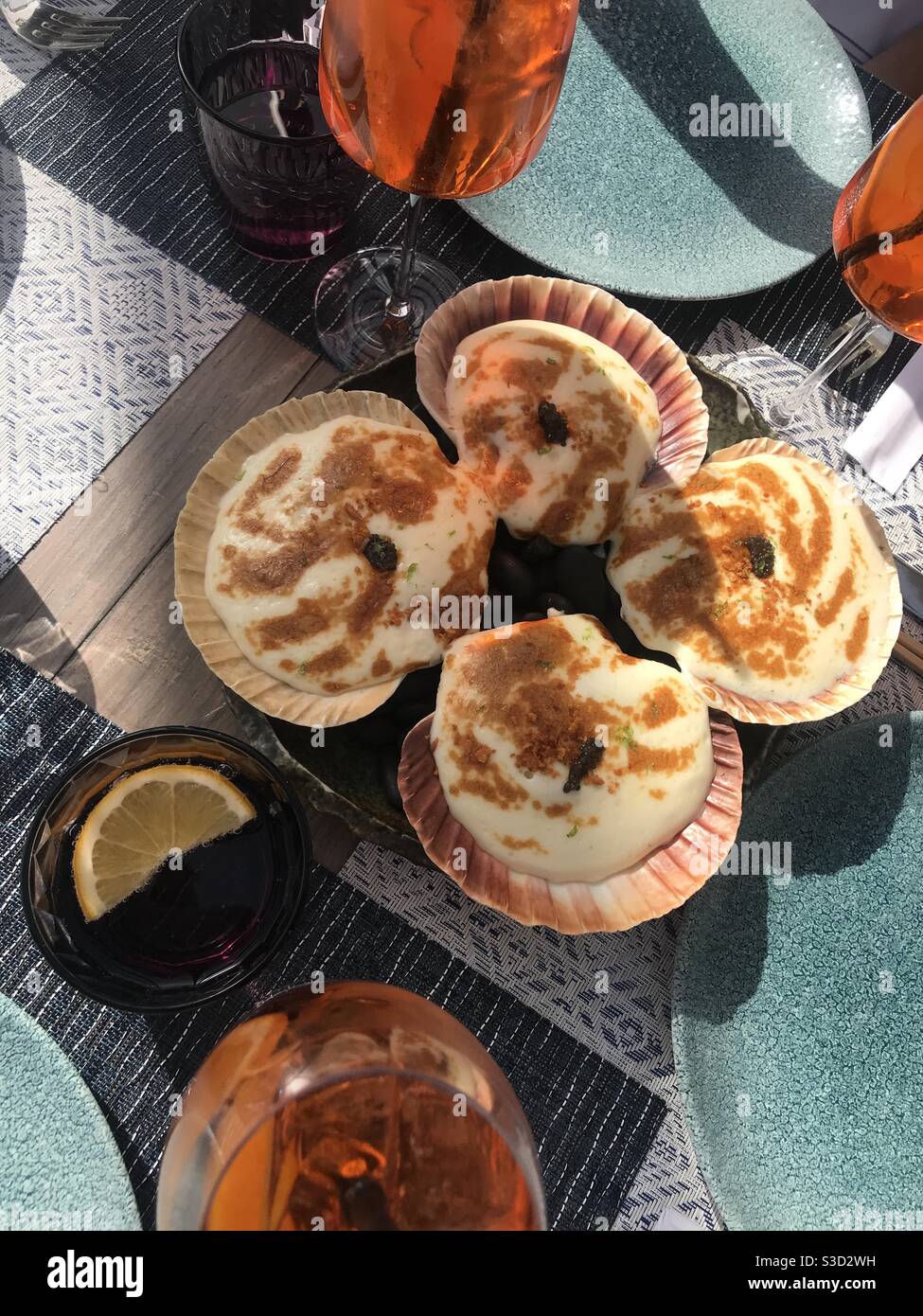 Noix de Saint-Jacques fraîches dans leur coquille avec du fromage fondu servi avec cocktails - Image de stock capturée avec un smartphone Noix de Saint-Jacques fraîches dans leur coquille avec du fromage fondu servi avec cocktails - Image de stock capturée avec un smartphone