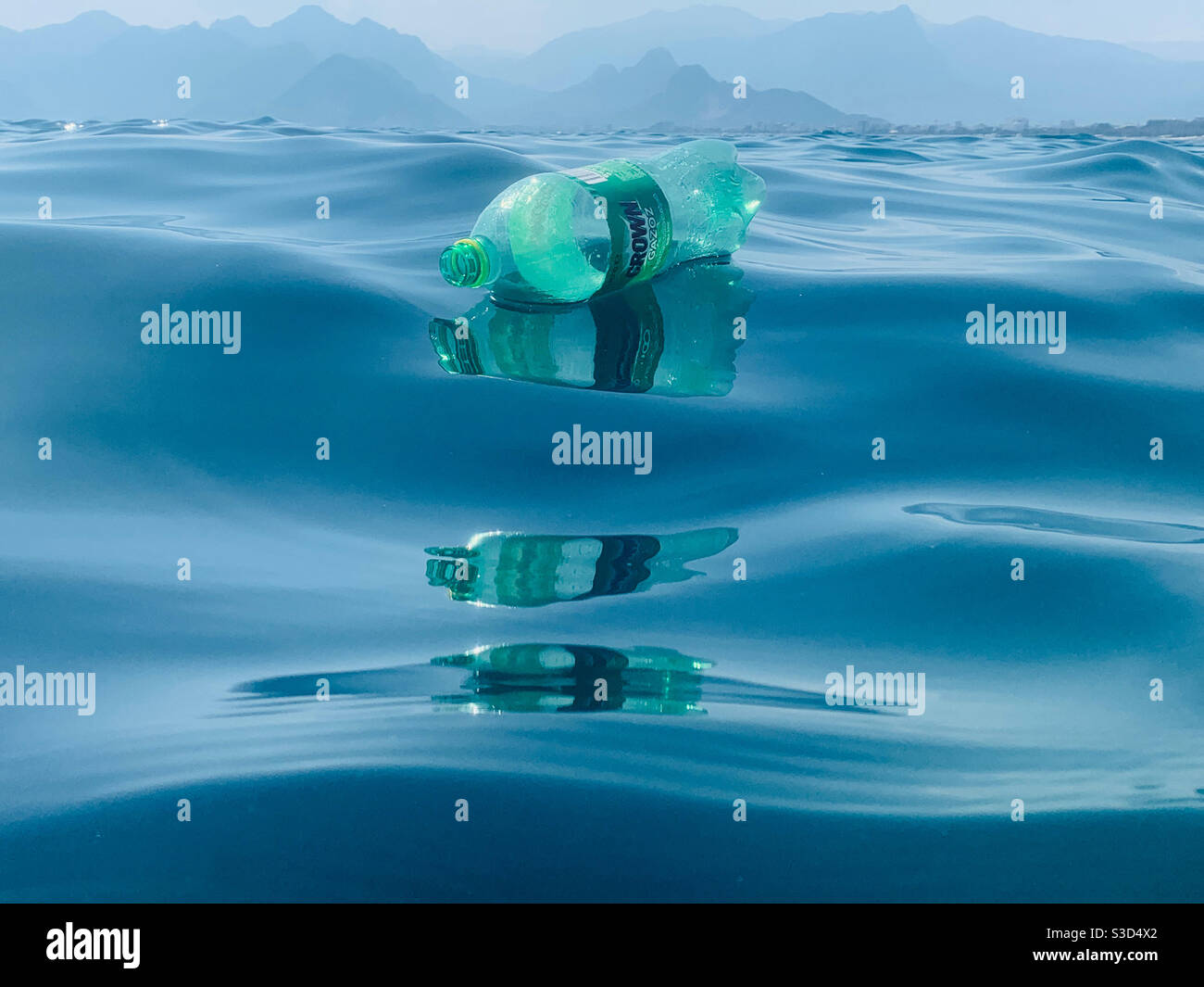 Bouteille en plastique vide à couronne verte flottante avec reflets brillants waves - photo primée Banque D'Images