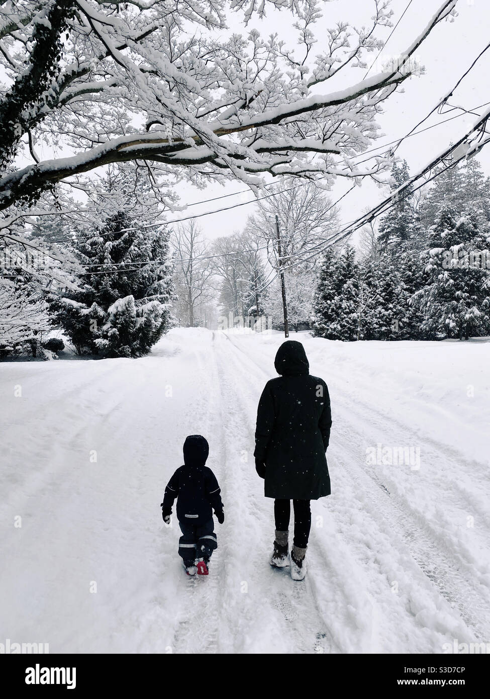 Une mère et un enfant de trois ans marchant dans une rue enneigée pendant une chute de neige dans le New Jersey. Banque D'Images