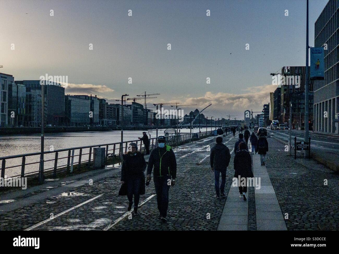 Les gens marchent au bord de la rivière Liffey près du point au pont East Link à Dublin en Irlande. Banque D'Images