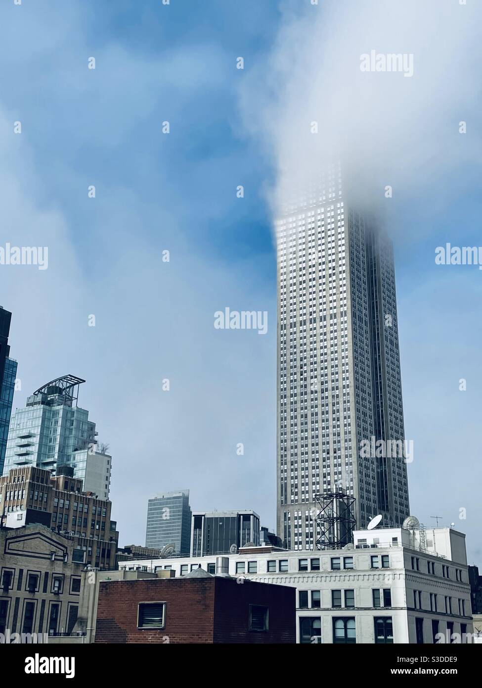 Un seul nuage blanc moelleux caresse le sommet de l'Empire State Building à Midtown Manhattan, New York, États-Unis - Image de stock capturée avec un smartphone