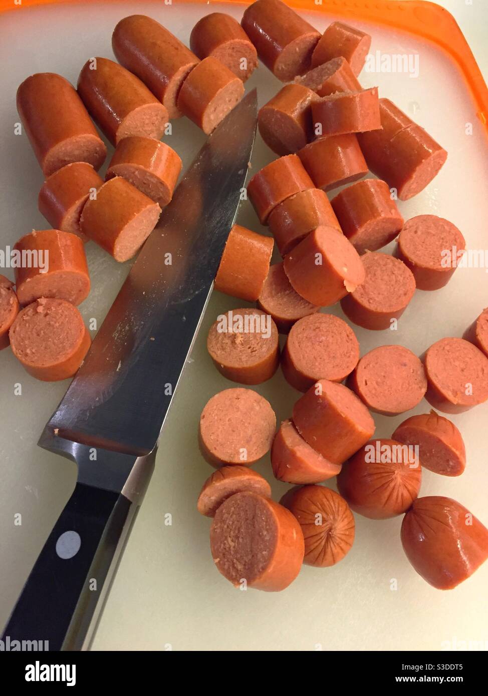 Des hot-dogs tranchés et un couteau de boucher sur une planche à découper de cuisine résidentielle, Etats-Unis - Image de stock capturée avec un smartphone
