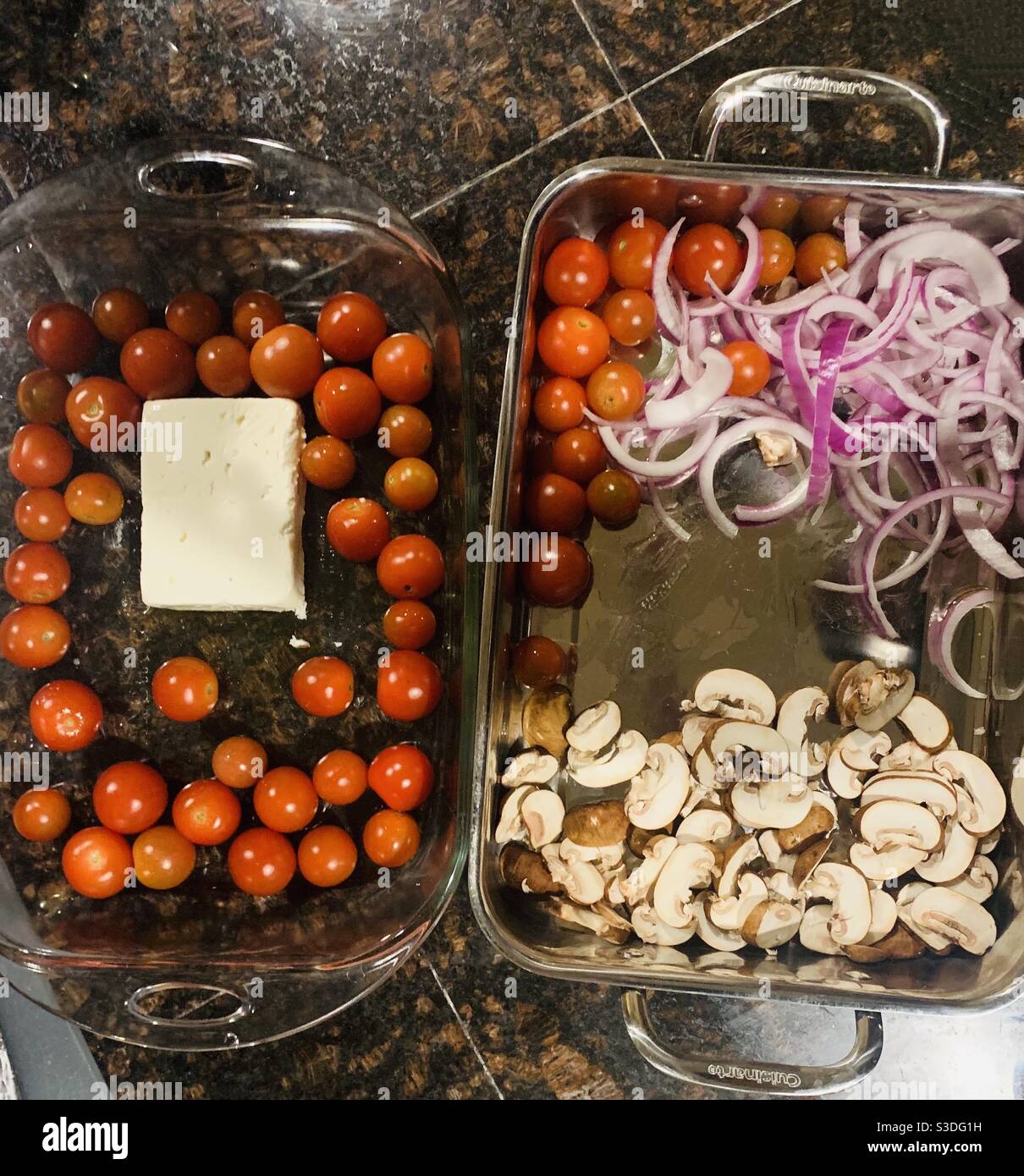 Préparation du dîner - ingrédients pour le dîner tomates cerises, fromage, oignons, champignons assaisonnés d'huile d'olive, en plaques de cuisson Banque D'Images