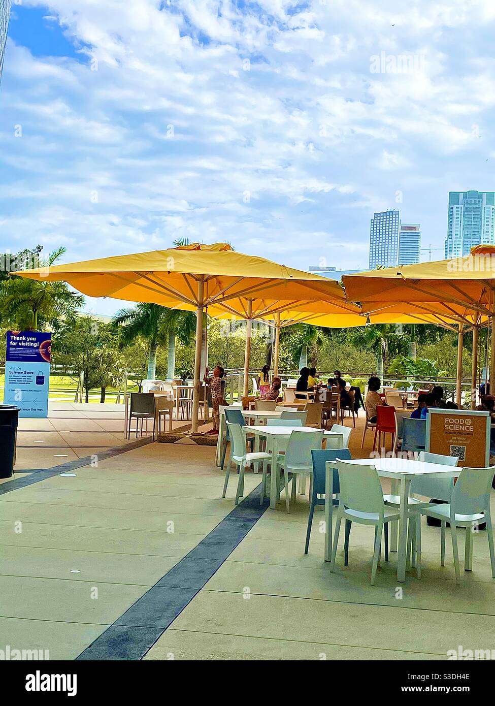 Les parasols jaunes lumineux ombragent les visiteurs du musée des sciences du gel Prendre des rafraîchissements dans la salle à manger extérieure - Image de stock capturée avec un smartphone