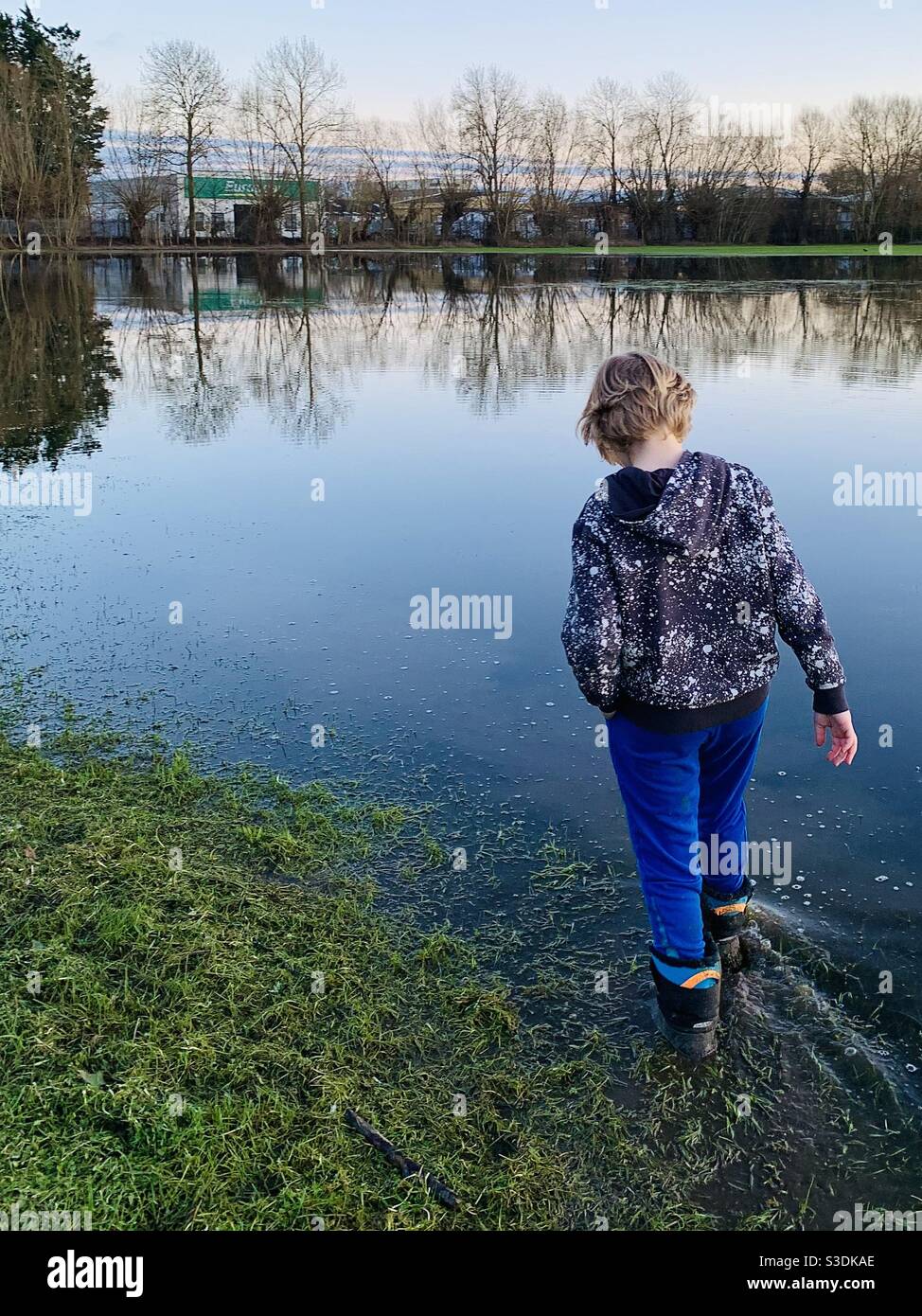 Garçon marchant dans un parc inondé Banque D'Images