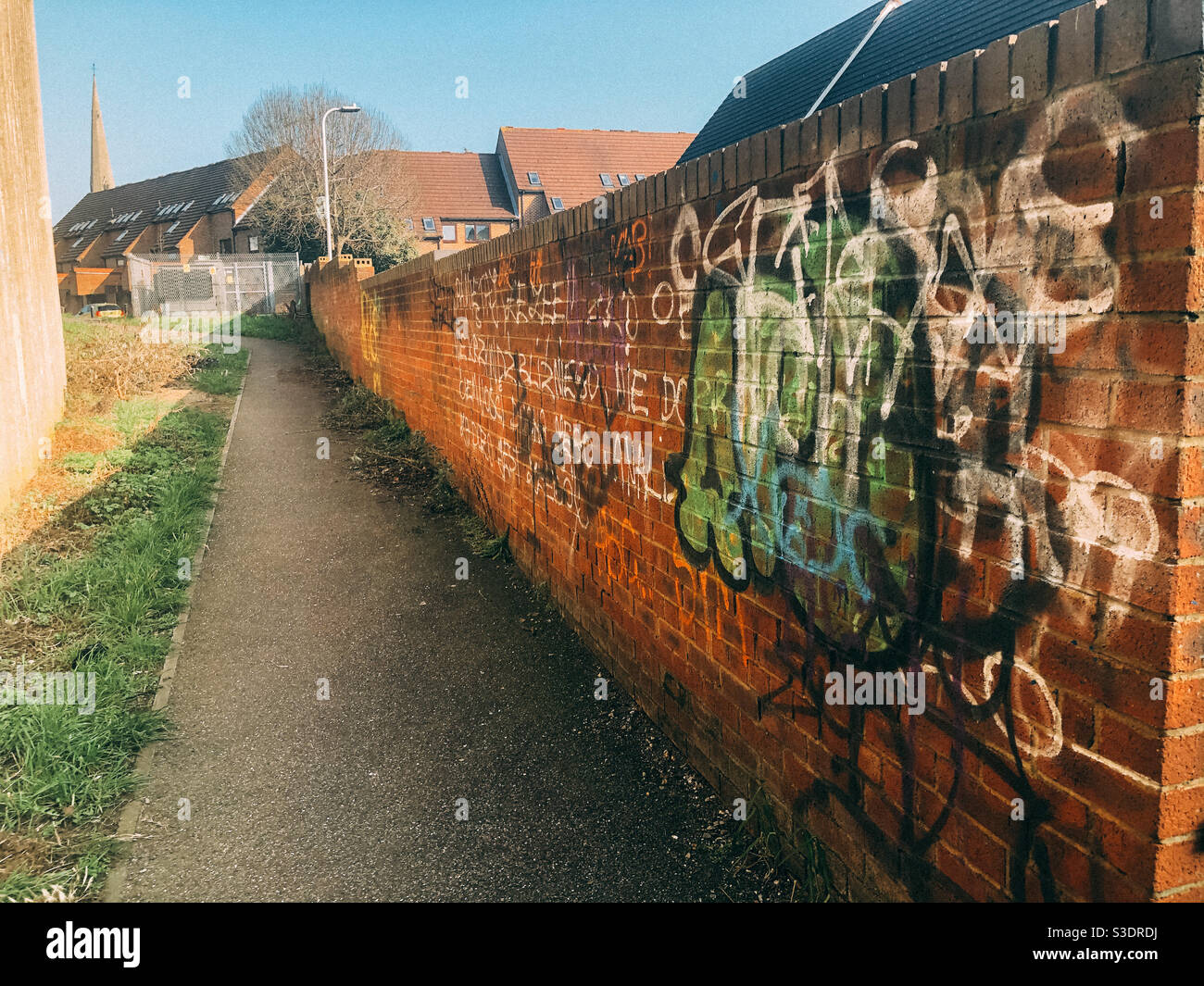 Graffitis sur un mur de briques à Reading, au Royaume-Uni, avec un sentier longeant. - Image de stock capturée avec un smartphone