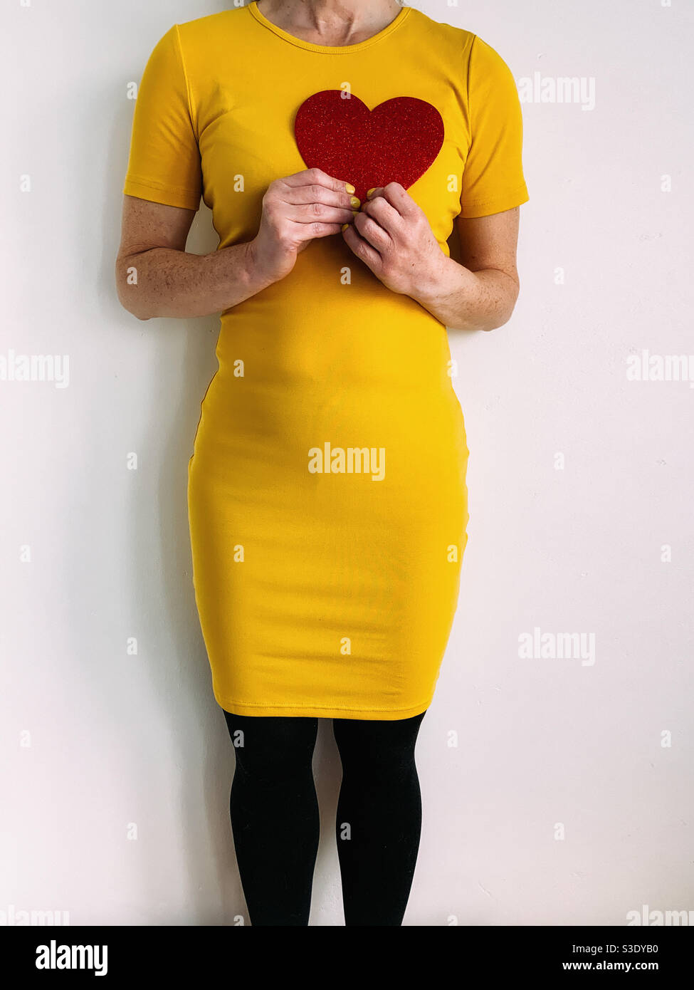 Femme portant un coeur rouge et une robe jaune Banque D'Images